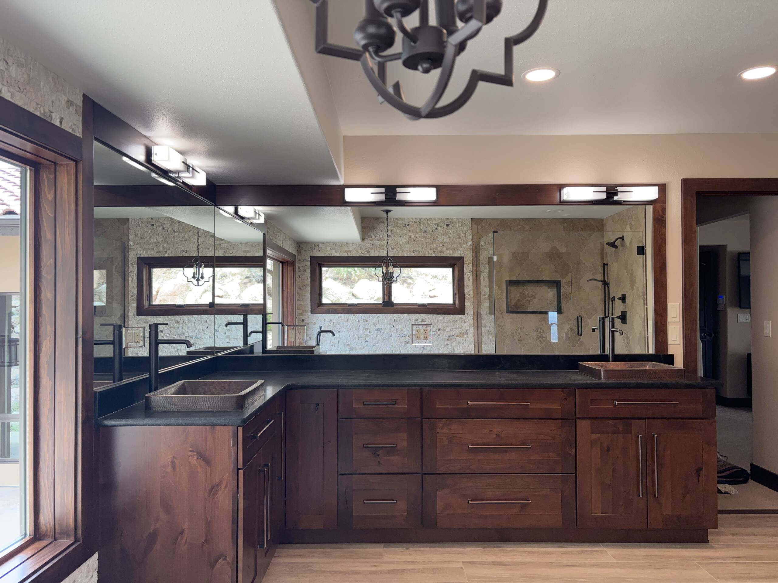 Primary bathroom remodel with dark wood vanity and black fixtures in Colorado Springs